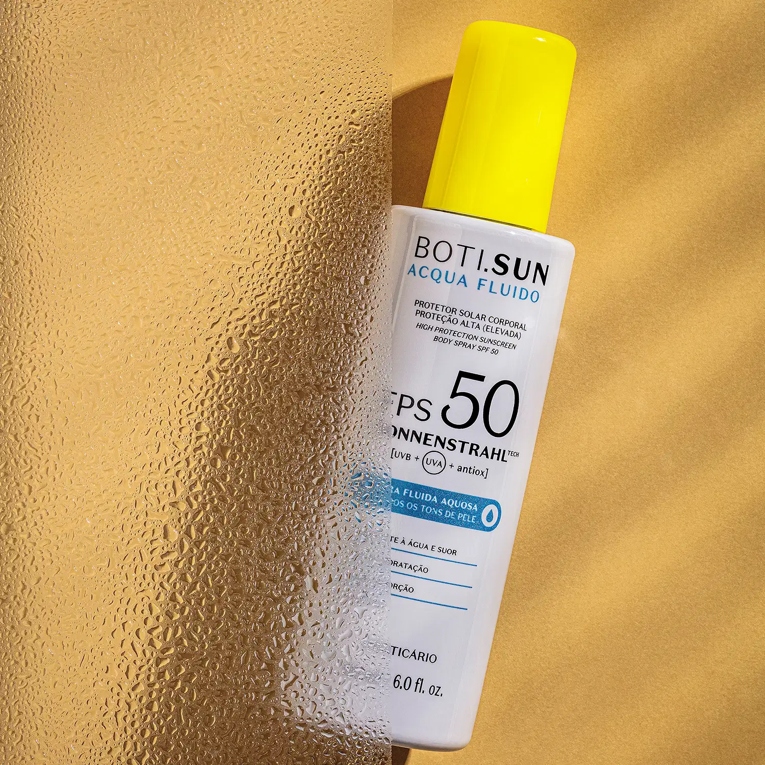 Frasco branco com tampa amarela, letras pretas e detalhe em azul, contendo 180ml de spray protetor solar corporal FPS 50 Acqua Fluído da marca Boti.Sun em fundo amarelo com sombras.