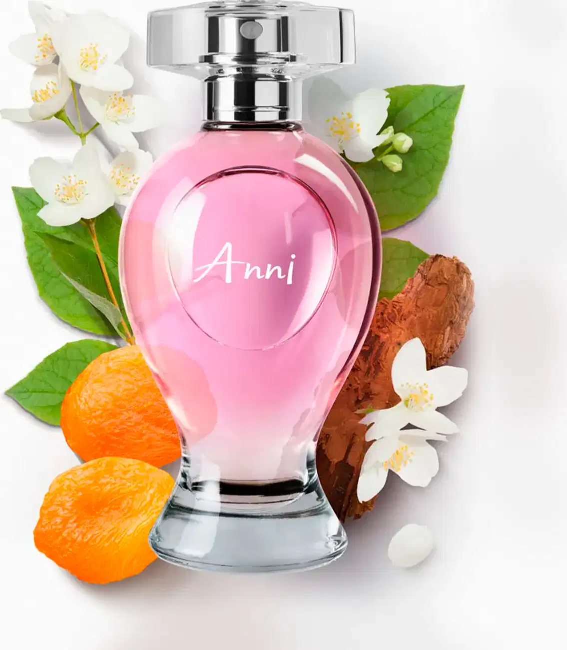 Vidro curvilíneo transparente com liquido rosa, pulverizador prateado e tampa cristal contendo desodorante colônia Boticollection Anni., circundado por flores brancas, frutas cítricas laranja e madeira em fundo branco.