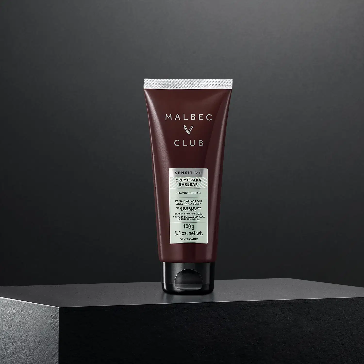Tubo de creme para barbear da marca Malbec Club em fundo preto. O produto é descrito como "Sensitive" e possui embalagem em tom marrom escuro com detalhes em branco.