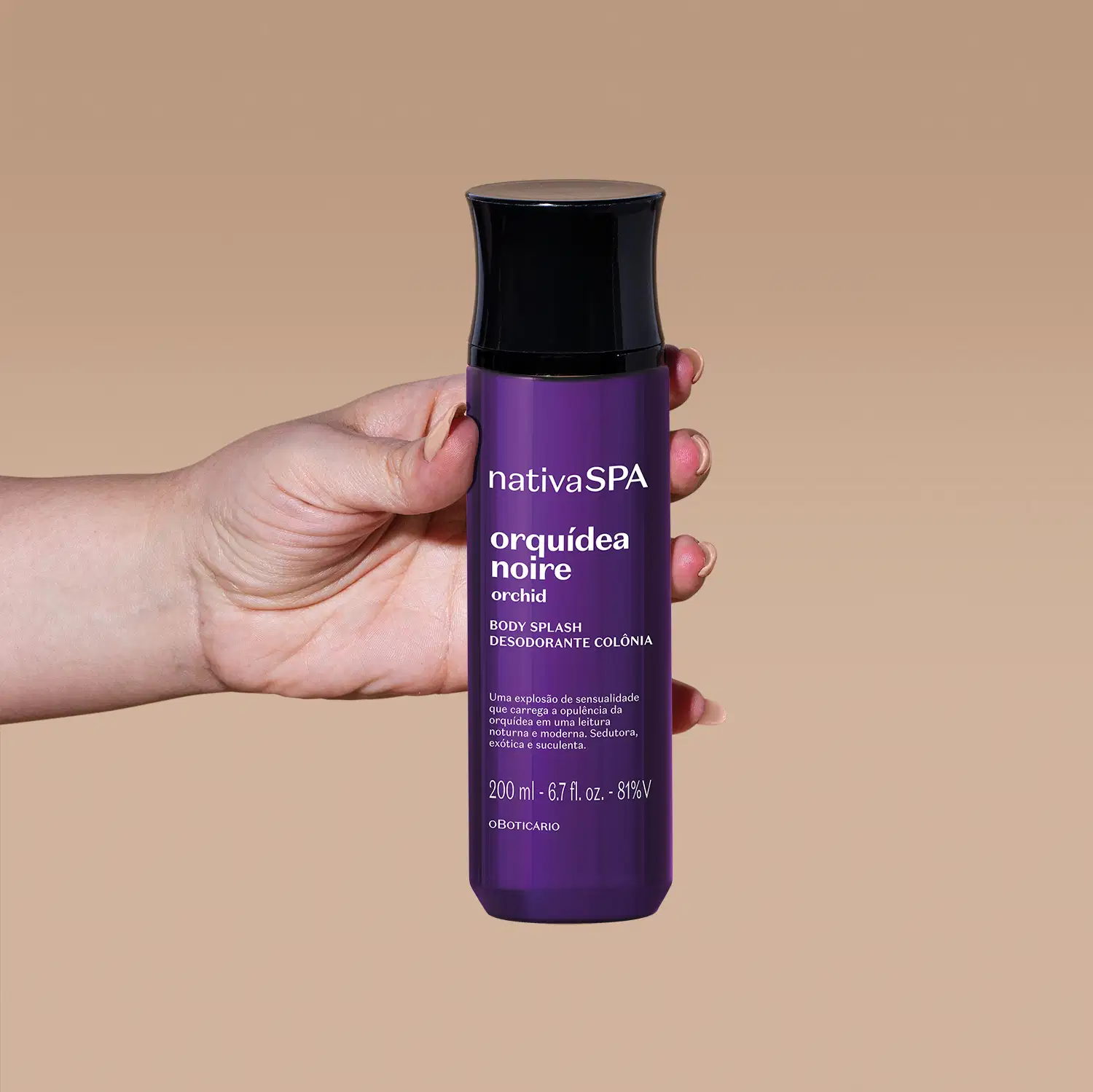 Mão segurando um frasco roxo escuro com tampa preta e letras brancas de body splash da marca Nativa SPA Orquídea Noire em um fundo com tons de bege.