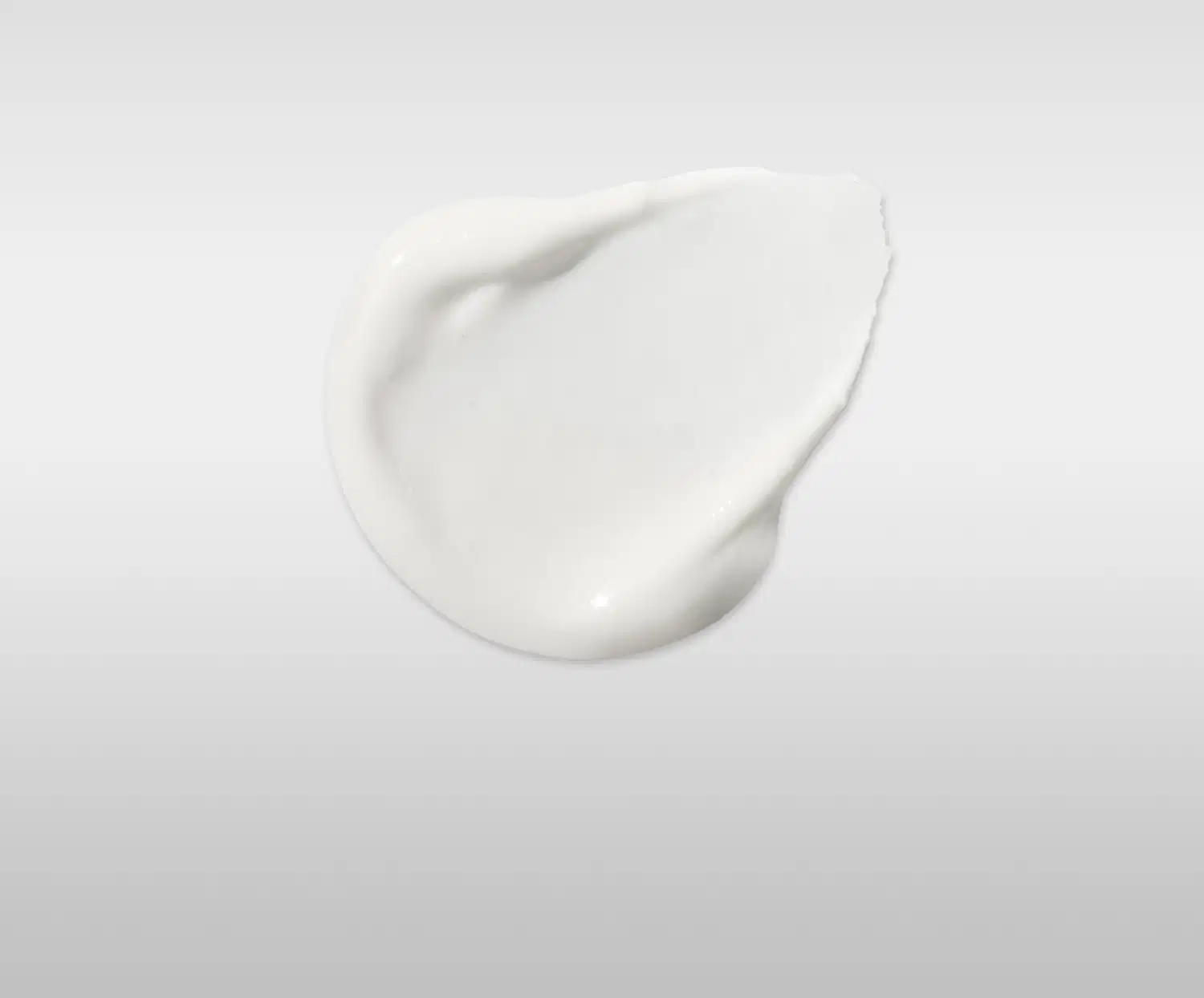 Textura de creme branco com acabamento brilhante e consistência densa, aplicado em superfície lisa com reflexo de luz destacando sua formulação cremosa.