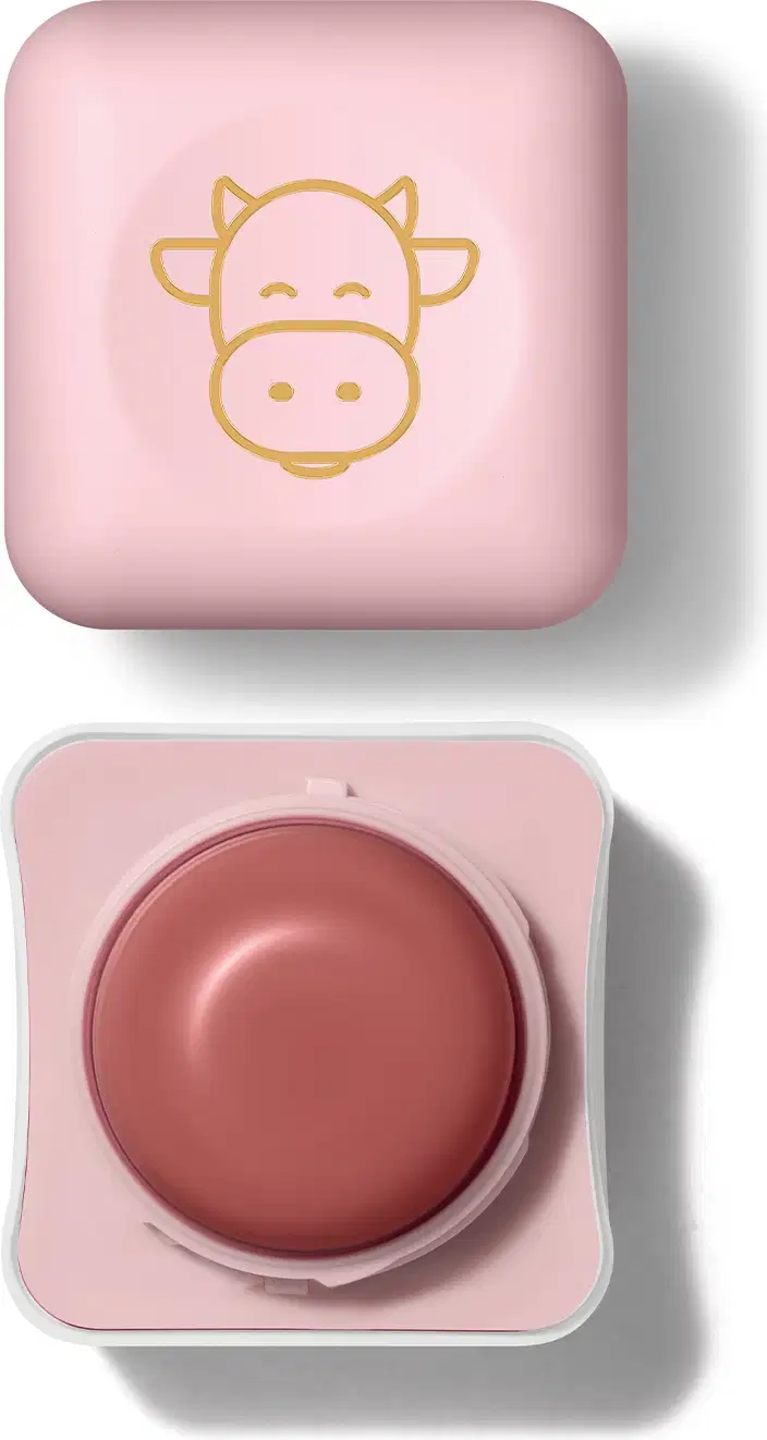 Pote compacto com cantos arredondados nas cores branca e rosa com roll-on rosa escuro e tampa rosa com ilustração de uma vaquinha contendo hidratante labial Intense & Cuide-se Bem Deleite.