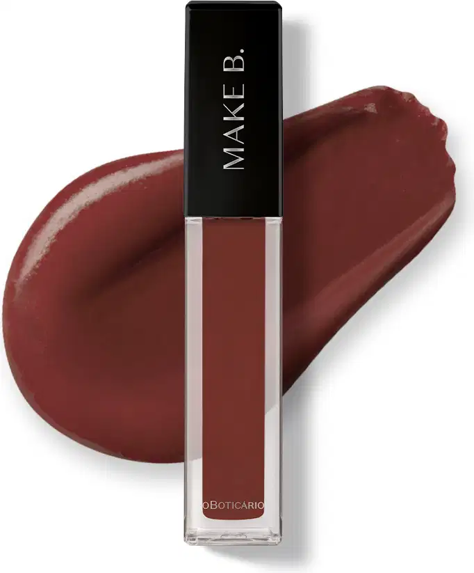 Batom líquido Mate Marrom Warm Cashmere da marca Make B. em tubo retangular transparente, produto de cor marrom intenso, tampa e haste pretas e esponja aplicadora macia., apresentado  textura sobre manchas do produto aplicado em superfície branca.