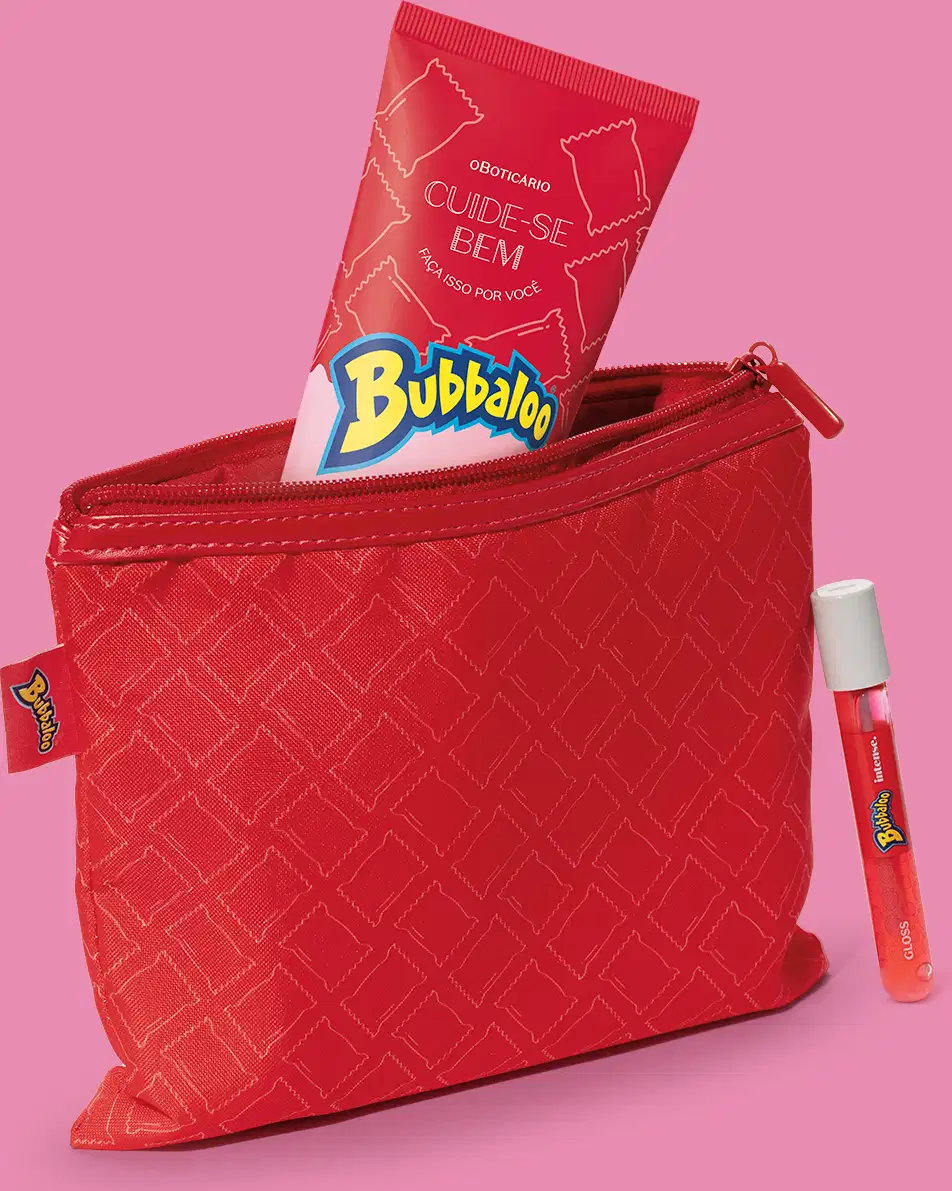 Nécessaire vermelha retangular da marca Cuide-se Bem Bubbaloo com padrão geométrico em dourado, zíper superior e etiqueta da marca Bubbaloo na lateral com um produto de mesma marca dentro, sobre fundo rosa.