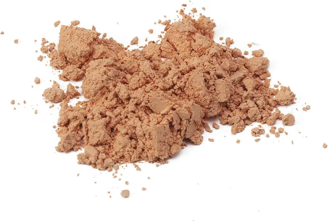 Pó solto em tom bege escuro com textura granulada e particulada, disperso sobre superfície branca, sugerindo se tratar da base em pó mineral cor 30 da marca Make B.