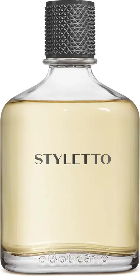 Frasco de fragrância Styletto com tampa preta texturizada e rótulo em letras pretas sobre fundo amarelo claro. O frasco é de vidro transparente, permitindo visualizar o conteúdo líquido.
