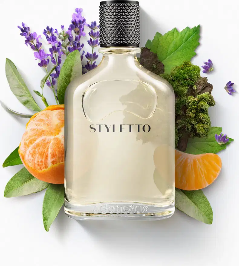 Ambiente de fragrância sofisticado, com flores e folhas verdes, laranja e roxo, destacando a garrafa da marca Styletto em fundo branco. Cenário elegante e natural, sugerindo um produto de beleza de alta qualidade.