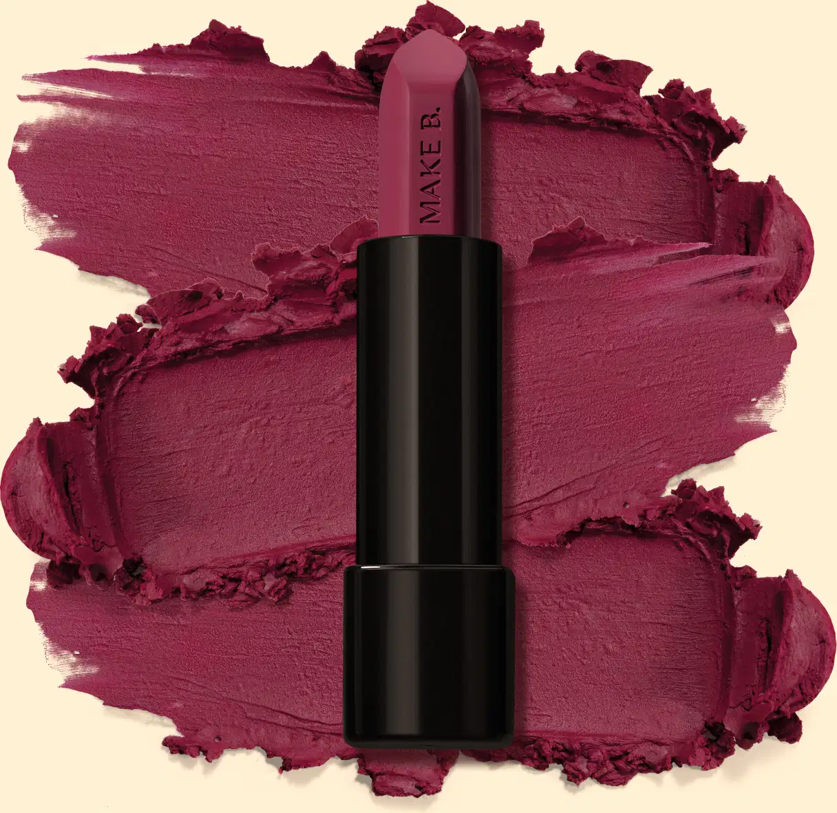 Batom mate na cor Violeta Violet da marga Make B., em tubo preto posicionado sobre uma amostra do produto na cor roxo intenso, sobre fundo bege claro.