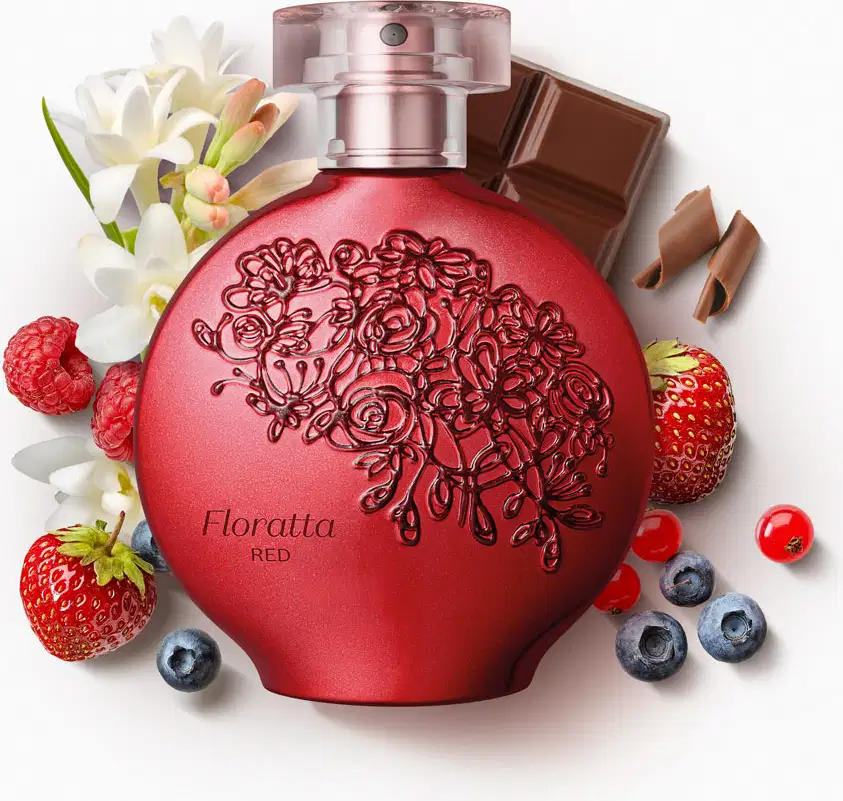 Perfume em frasco redondo de vidro vermelho com detalhes florais gravados. Rótulo "Floratta Red" visível. Acompanhado de flores brancas, morangos, mirtilos, pedaços de chocolate.