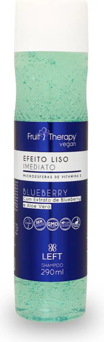 A imagem mostra um frasco transparente com rótulo azul e tampa branca de 290ml do shampoo da linha Fruit Therapy Vegan Blueberry, onde é possível ver o conteúdo esverdeado por dentro. O design traz informações sobre benefícios e composição.