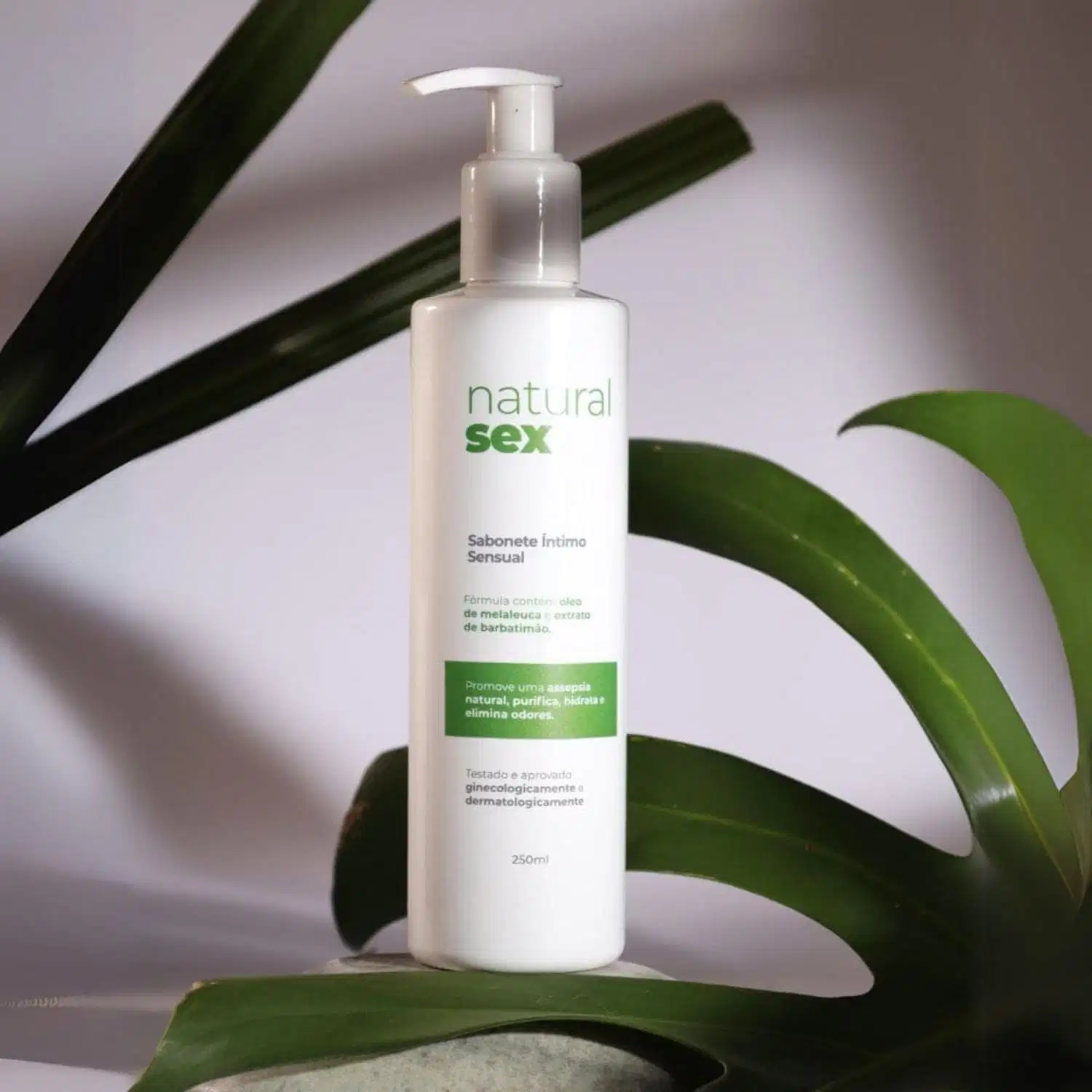 Sabonete Íntimo Líquido Natural Sex com fundo destacando folhas verdes de plantas