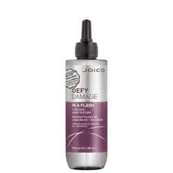 É um produto de tratamento capilar da marca Joico. A embalagem é um frasco que tem um aplicador preto na parte superior. O rótulo na frente é predominantemente branco e roxo. O nome do produto "Defy Damage In a Flash" está escrito em letras grandes;