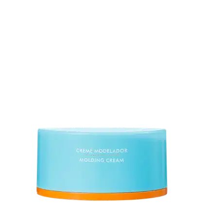A imagem mostra o Creme Modelador Moroccanoil Molding Cream 100ML, em embalagem redonda de plástico azul claro com detalhes em laranja. Está impresso na parte frontal da embalagem em letras brancas: Creme Modelador Molding Cream.