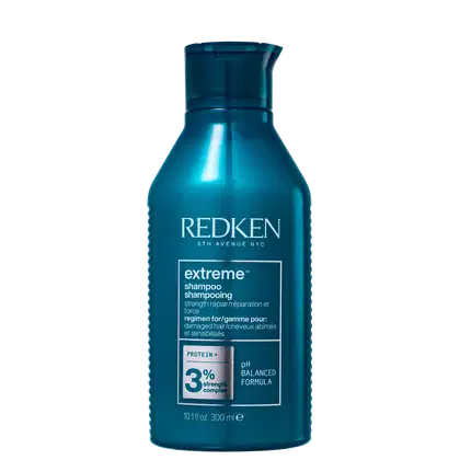 Frasco de shampoo Redken Extreme, com fórmula pH balanceada, contendo 3% de complexo de proteína, para cabelos danificados. Embalagem de 300 ml na cor azul escuro.