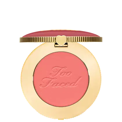 Blush compacto de maquiagem com embalagem redonda dourada. A tampa superior é amarronzada com a inscrição "Too Faced" em letras cursivas. Um pequeno coração dourado adorna o centro da tampa.
