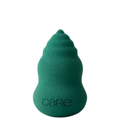 A imagem mostra uma esponja de maquiagem verde e com o termo "care" impresso na base do produto.
