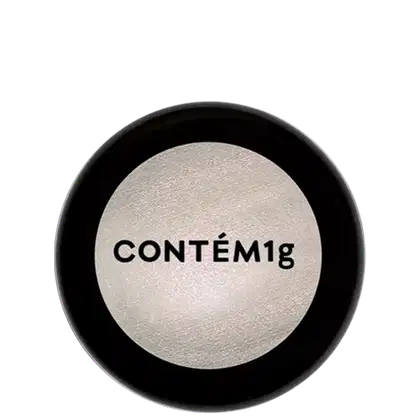 A imagem mostra uma embalagem de pó iluminador cor prateada e no centro, a logo da marca em preto.