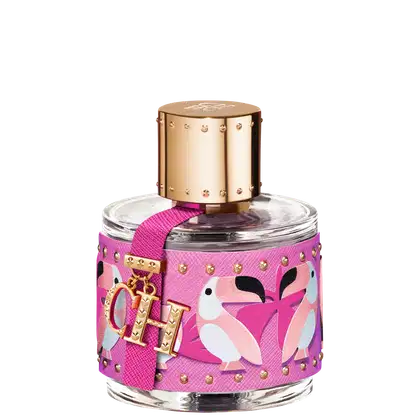 A imagem mostra um frasco de perfume, em vidro, redondo, com tampa dourada, envolto em uma capa texturizada rosa com pássaros branco e rosa e detalhes dourados. Tem também um chaveiro pendurado com as letras CH, logo da marca.