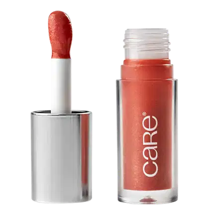 A imagem mostra o Lip Oil de Care Natural Beauty. Possui uma embalagem transparente de plástico, semelhante a um batom líquido. Possui cor rosa queimado e a embalagem apresenta o logotipo "Care" em letras brancas. A tampa prata com aplicador.