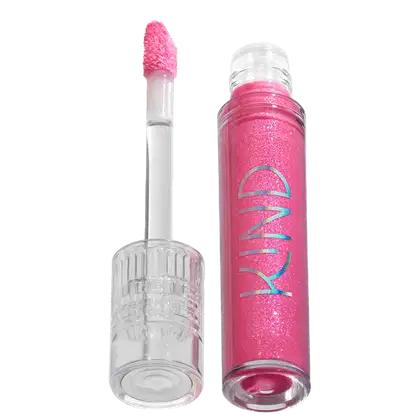 A imagem mostra a tampa da embalagem do gloss, com o aplicador virado pra cima, semelhante a uma tampa de batom, transparente e cilíndrica. Ao lado, o frasco do gloss, com o produto de cor rosa e com a palavra KIND escrito na embalagem.
