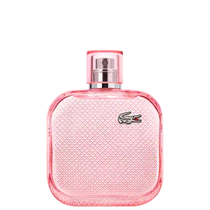 A imagem mostra um frasco de perfume da marca Lacoste. O frasco é retangular, com cantos arredondados e acabamento texturizado em relevo, todo em rosa, e com o desenho de um crocodilo, símbolo da marca, no canto superior direito.