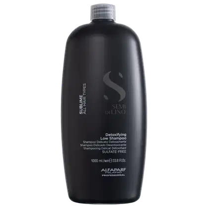 A imagem mostra o shampoo Semi di Lino Sublime Detoxifying Low 1 litro, da marca Alfaparf Milano. Apresenta o rótulo com o nome Semi di Lino - Detoxifying Low Shampoo.  A embalagem preta com o logo e informações em branco dá um visual sofisticado.