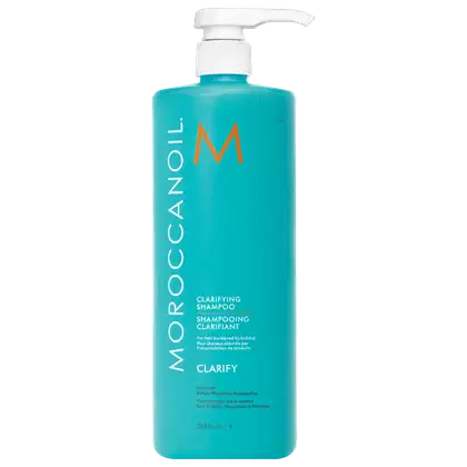 A imagem mostra o Shampoo Purificante Clarify 1L da marca Moroccanoil. Embalagem plástica na cor azul turquesa, com letras brancas e pretas e logotipo da marca em laranja. O frasco tem uma bomba dosadora branca na parte superior.