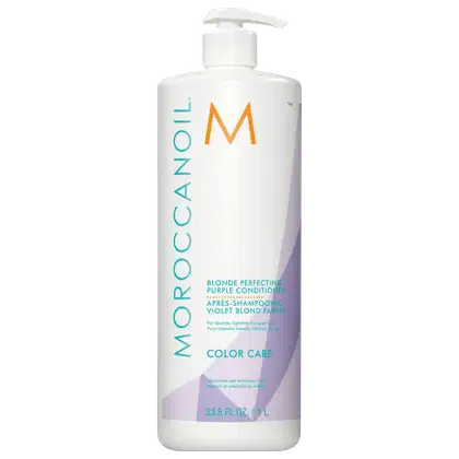 A imagem mostra o Condicionador Moroccanoil Color Care Blonde Perfecting Purple 1L, um frasco cilíndrico predominantemente branco, com detalhes em tons de roxo, laranja e azul. As informações do produto estão escritas em inglês e francês,