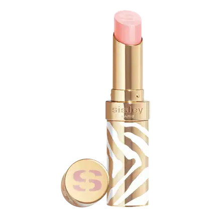 Bálsamo labial em embalagem dourada com detalhes brancos e marrons em padrão zebrado. A cor do hidratante é rosa claro. O rótulo "Sisley Paris" está visível na embalagem dourada. Há também um pequeno espelho compacto dourado com o logotipo "S".