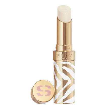 Bálsamo labial em embalagem dourada com detalhes brancos e marrons em padrão zebrado. A cor do hidratante é transparente. O rótulo "Sisley Paris" está visível na embalagem dourada. Há também um pequeno espelho compacto dourado com o logotipo "S".