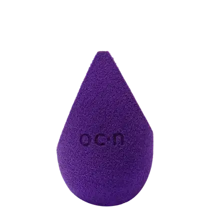 Esponja de maquiagem roxo escuro com textura aveludada. Formato de gota com a palavra "Océane" impressa em relevo na superfície.