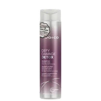Shampoo detox Defy Damage da marca Joico. Embalagem cilíndrica roxa com detalhes prateados. Rótulo indicando que remove metais, minerais traço e cloro dos cabelos. Volume de 10.1 fl oz / 300ml.