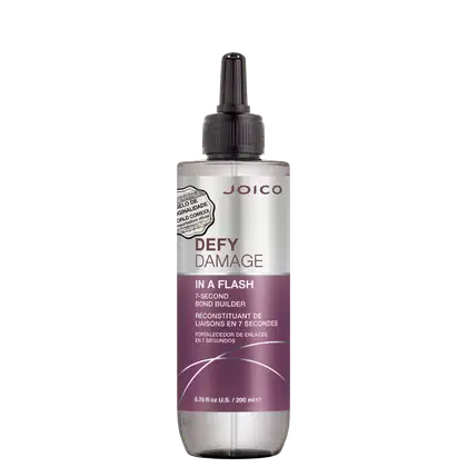 É um produto de tratamento capilar da marca Joico. A embalagem é um frasco que tem um aplicador preto na parte superior. O rótulo na frente é predominantemente branco e roxo. O nome do produto "Defy Damage In a Flash" está escrito em letras grandes;
