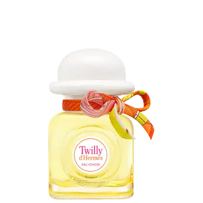 Frasco transparente onde é possível ver o líquido amarelo por dentro. Formato quadrado, com tampa arredondada branca e um laço laranja amarrado.