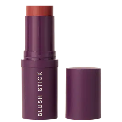 A imagem mostra o Blush Stick da marca Océane em embalagem cilíndrica de plástico roxo com o nome do produto em letras brancas. A embalagem está aberta mostrando um pouco da cor do blush em tom de vermelho e a tampa está ao lado.