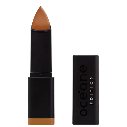 A imagem mostra a Base em Bastão Océane Edition Foundation Stick: embalagem preta retangular com o logotipo "Océane Edition" impresso em relevo na parte frontal. A base tem formato triangular.