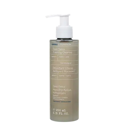 Frasco de limpador facial espumante da marca Korres, com rótulo em inglês e grego indicando "Deep Detox Foaming Cleanser" e "Detoxifiant Intense". O produto possui embalagem branca com detalhes em bege e azul, com bomba doseadora.
