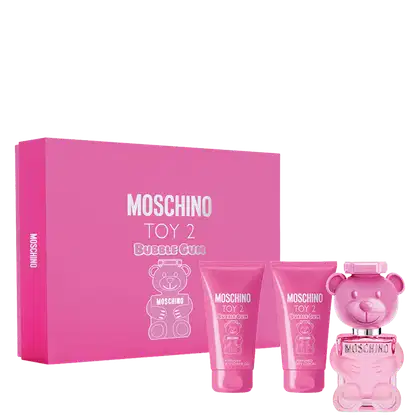 Caixa retangular rosa com o logotipo e nome do produto em letras brancas. Frasco de perfume rosa em formato de urso, tubo de loção corporal e tubo de shower gel, ambos na cor rosa.