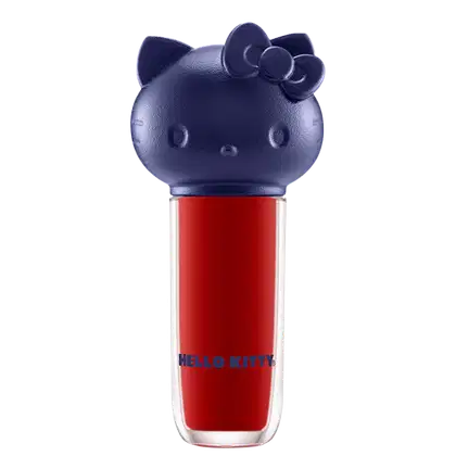Produto de maquiagem em formato cilíndrico com a cabeça da personagem Hello Kitty como tampa. A parte superior é azul escuro com detalhes que representam os olhos, orelhas e laço da Hello Kitty. É possível ver a cor do produto pelo corpo transparente.