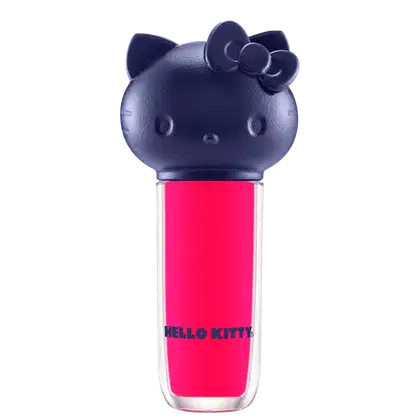 Produto de maquiagem em formato cilíndrico com a cabeça da personagem Hello Kitty como tampa. A parte superior é azul escuro com detalhes que representam os olhos, orelhas e laço da Hello Kitty. É possível ver a cor do produto pelo corpo transparente.