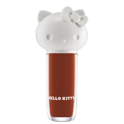 Maquiagem em formato cilíndrico com a cabeça da personagem Hello Kitty como tampa. A parte superior é branca com detalhes em relevo que representam os olhos, orelhas e laço da Hello Kitty. É possível ver a cor do produto pelo corpo transparente.