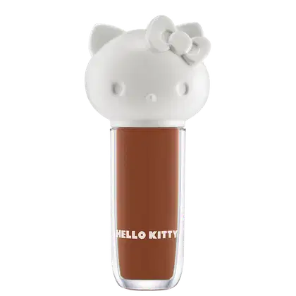 Maquiagem em formato cilíndrico com a cabeça da personagem Hello Kitty como tampa. A parte superior é branca com detalhes em relevo que representam os olhos, orelhas e laço da Hello Kitty. É possível ver a cor do produto pelo corpo transparente.