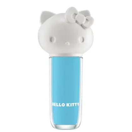 Maquiagem em formato cilíndrico com a cabeça da personagem Hello Kitty como tampa. A parte superior é branca com detalhes em relevo que representam os olhos, orelhas e laço da Hello Kitty. É possível ver a cor do produto pelo corpo transparente.