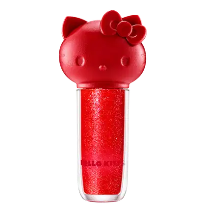 Maquiagem em formato cilíndrico com a cabeça da personagem Hello Kitty como tampa. A parte superior é vermelha com detalhes em relevo que representam os olhos, orelhas e laço da Hello Kitty. É possível ver a cor do produto pelo corpo transparente.