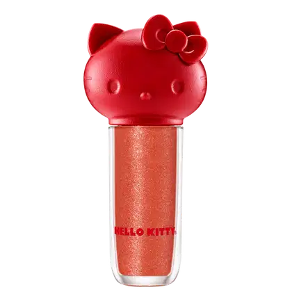 Maquiagem em formato cilíndrico com a cabeça da personagem Hello Kitty como tampa. A parte superior é vermelha com detalhes em relevo que representam os olhos, orelhas e laço da Hello Kitty. É possível ver a cor do produto pelo corpo transparente.