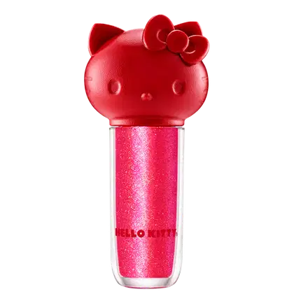 Maquiagem em formato cilíndrico com a cabeça da personagem Hello Kitty como tampa. A parte superior é vermelha com detalhes em relevo que representam os olhos, orelhas e laço da Hello Kitty. É possível ver a cor do produto pelo corpo transparente.