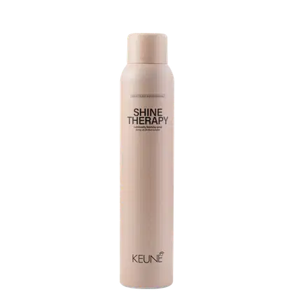 A imagem mostra o produto Shine Therapy da marca Keune. Embalagem cilíndrica na cor bege claro. Rótulo com o nome do produto "Shine Therapy" e descrição "Luminously finishing spray" (Spray de acabamento luminoso) em letras escuras.