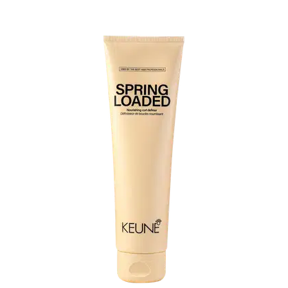 A imagem mostra o produto Spring Loaded da marca Keune. A embalagem é um tubo plástico de cor bege claro. O nome do produto "Spring Loaded Nourishing Curl Definer" está impresso em letras marrons.