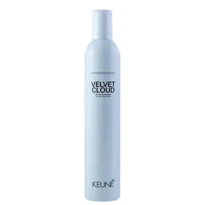 A imagem mostra a Mousse Volumadora Velvet Cloud da marca Keune. É apresentado em um frasco cilíndrico branco azulado opaco. Exibe o nome do produto "Velvet Cloud" em letras pretas maiúsculas, seguido da descrição "Mousse volume foam" em letras menores.