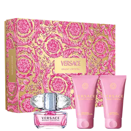 A imagem mostra um kit com o perfume Bright Crystal, shower gel e body lotion, da Versace. Ao fundo uma caixa com estampa floral.
